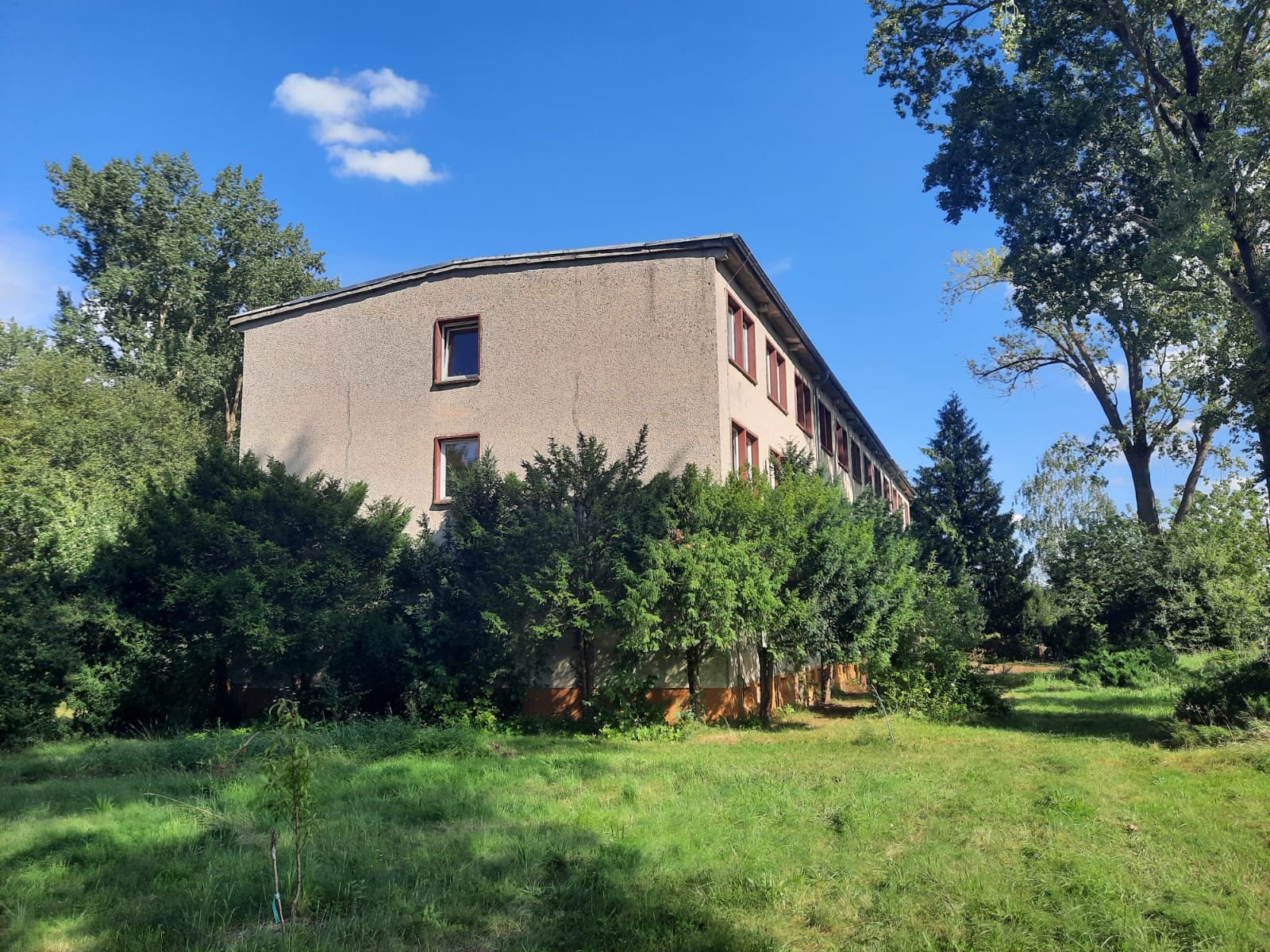 Wohnen im Ashram Gurudham – Seitenansicht des Seminarhauses mit Garten und Bäumen in ruhiger Natur