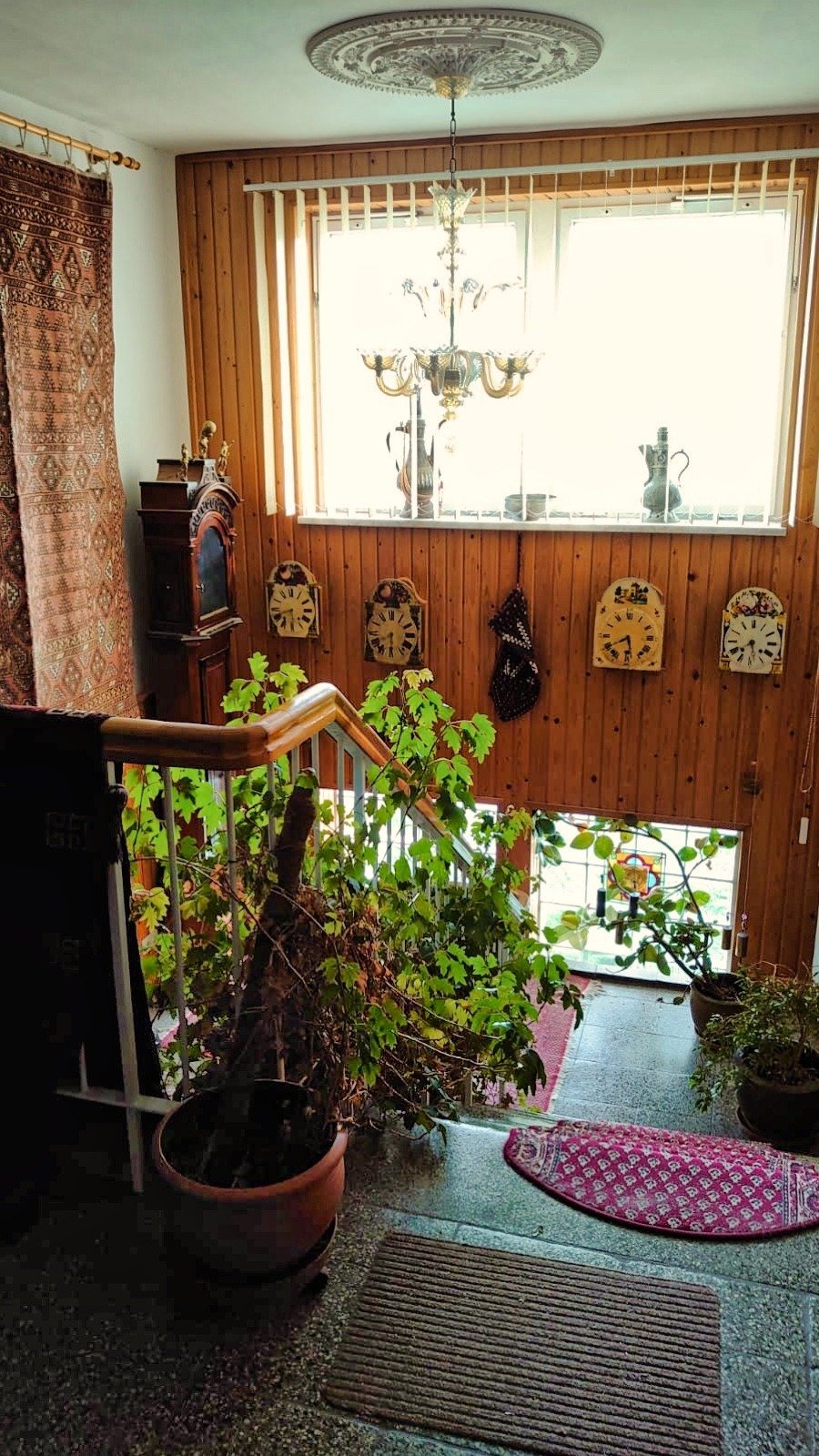 Treppenhaus im Hauptgebäude des Ashram Gurudham mit Pflanzen, Teppichen und warmem Holz – Wohnen im Ashram